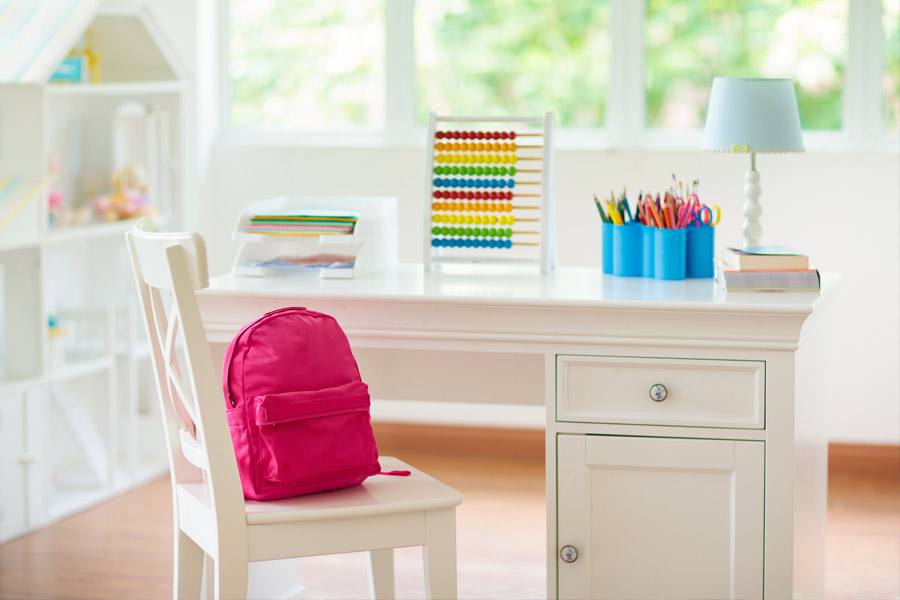 White wooden desk with drawer and cabinet, a pink backpack sits on a matching chair.